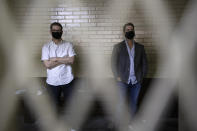 The sons of former Panamanian President Ricardo Martinelli, Ricardo Martinelli Linares, right, and his brother Luis Enrique stand inside a holding cell at the judicial court building in Guatemala City, Tuesday, July 7, 2020. The brothers were detained Monday on an international warrant from Interpol on charges of conspiracy to commit money laundering. (AP Photo/Moises Castillo)