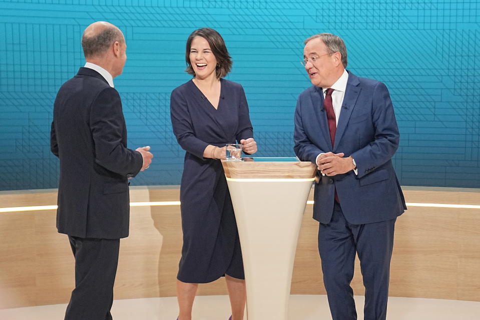 Die Kanzlerkandidaten Annalena Baerbock, Armin Laschet und Olaf Scholz stehend lachend im Studio bei den Aufzeichnungen zum TV-Triell im ARD und ZDF.