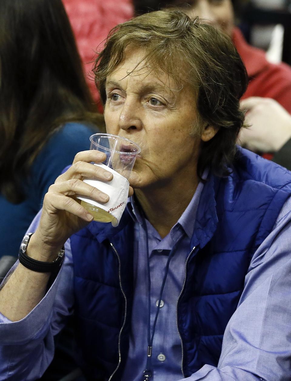 British musician Paul McCartney drinks ahead of the Atlanta Hawks versus Brooklyn Nets NBA basketball game at the O2 Arena in London, Thursday, Jan. 16, 2014. (AP Photo/Kirsty Wigglesworth)