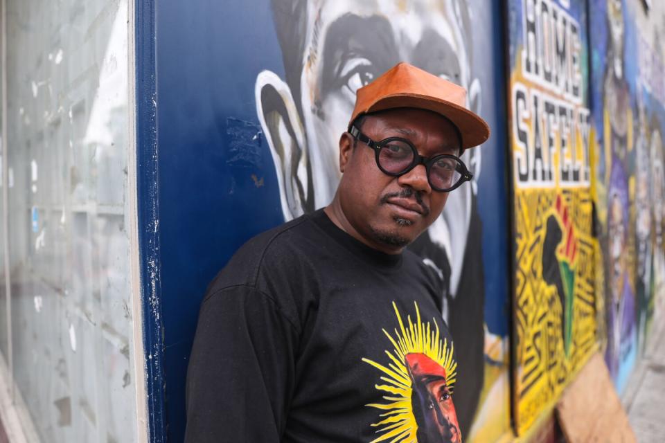 A man stands next to a wall featuring a mural in Leimert Park.