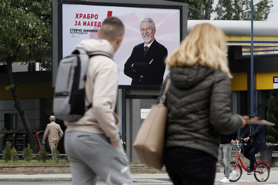 People walk past election poster of the presidential candidate Stevcho Jakimovski, the mayor of Karpos, a municipality in the capital Skopje, in a street in Skopje, North Macedonia, on Monday April 22, 2024. Voters go to the polls in North Macedonia on Wednesday April 24 for the first round of presidential elections, the seventh such election since the Balkan country gained independence from the former Yugoslavia in 1991, where seven candidates are vying for the largely ceremonial position. (AP Photo/Boris Grdanoski)