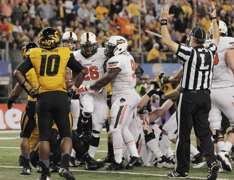 After scoring a touchdown against Missouri, Oklahoma State running back Desmond Roland (26) celebrates with fullback Kye Staley (9) as safety Brock Bondurant (10) looks on during the second half of the Cotton Bowl NCAA college football game, Friday, Jan. 3, 2014, in Arlington, Texas. (AP Photo/Brandon Wade)