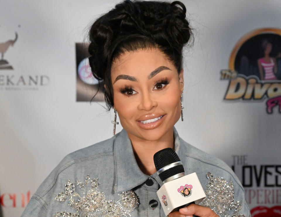 Blac Chyna in a denim jacket with embellishments, holding a microphone