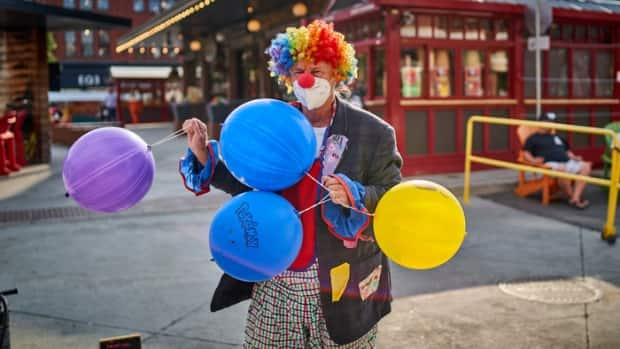 A busker in a clown wig and a COVID-19 mask performs in Ottawa's ByWard Market on July 5, 2021.          (David Richard/Radio-Canada - image credit)