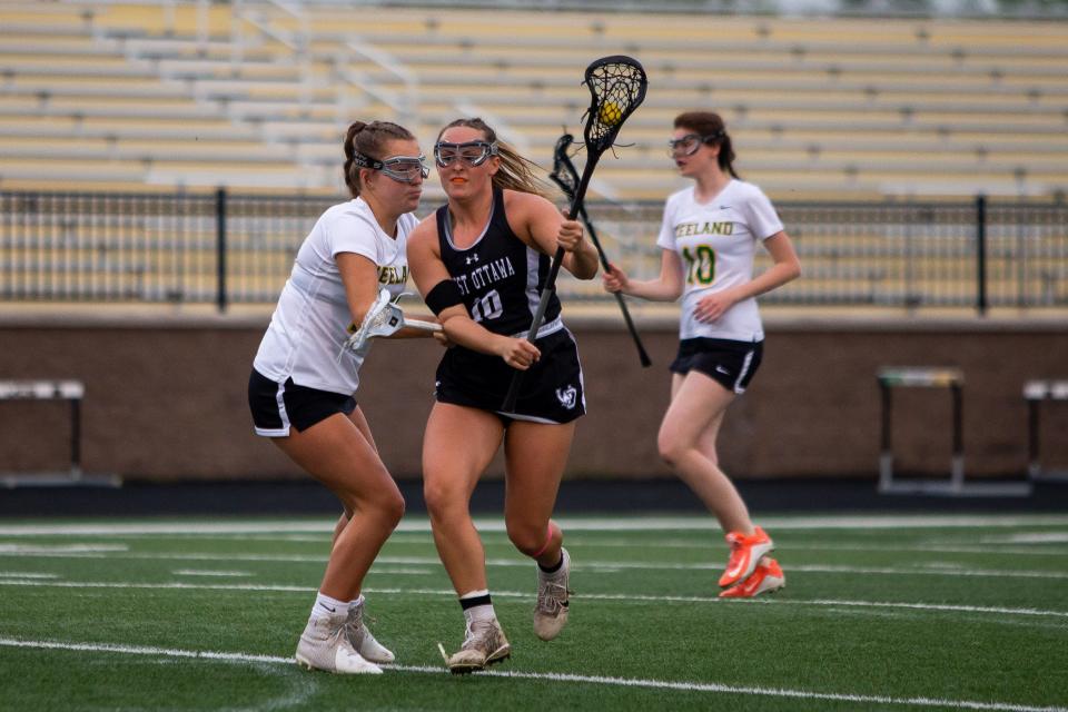 West Ottawa's Ella Spooner looks to score as she pushes past the Zeeland defense Wednesday, May 11, 2022, at Zeeland High School. 