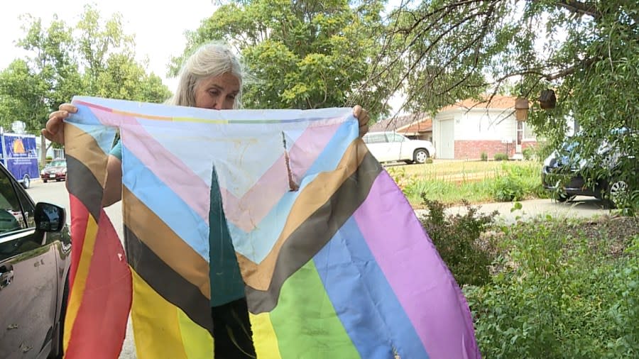 Woman holds up a shredded pride flag