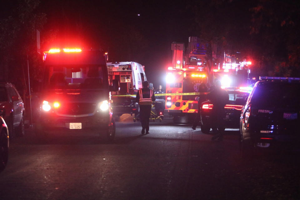 Police and emergency personnel work at the scene of a shooting at a backyard party in southeast Fresno, California. 