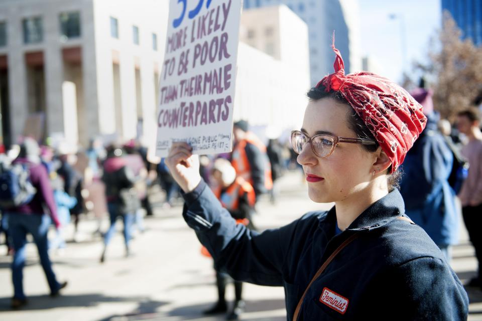 Lily Williams of Denver, Colorado dressed as Rosie the Riveter, holds up a sign as demonstrators march past her during during the Women's March in Denver, Colorado on January 19, 2019. - Thousands of women gathered across the United States for their annual message opposing Donald Trump and supporting women's rights. (Photo by Jason Connolly / AFP)        (Photo credit should read JASON CONNOLLY/AFP via Getty Images)