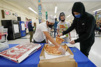 West Brooklyn Community High School students grab slices of pizza in the cafeteria, Thursday, Oct. 29, 2020, in New York, following a current events/trivia quiz for those who showed up on a rainy day. The high school is a "transfer school," catering to a students who haven't done well elsewhere, giving them a chance to graduate and succeed. (AP Photo/Kathy Willens)