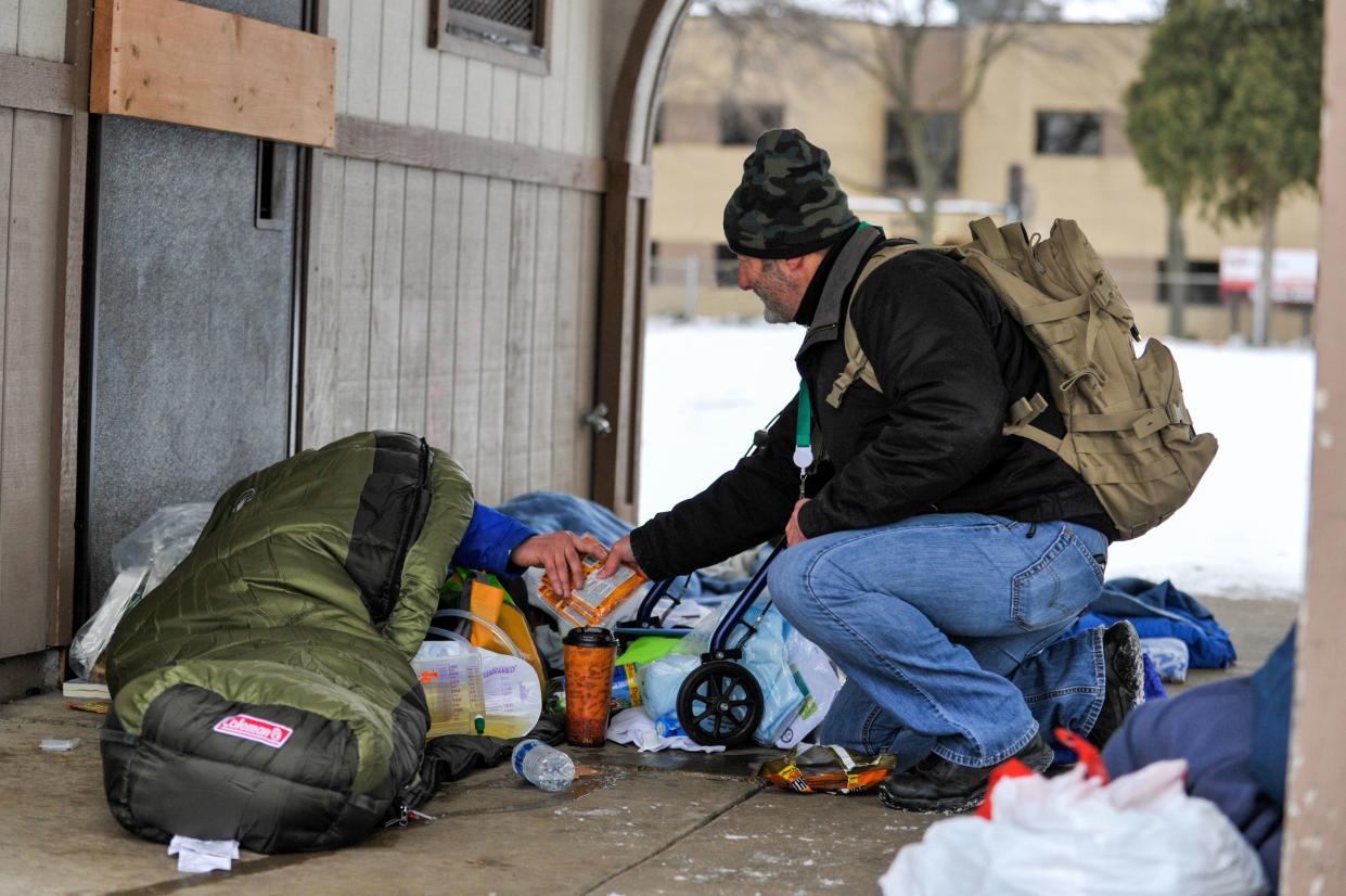 Paul VanHandel of Newcap gives a few hand warmers to an unsheltered homeless individual in St. John's Park in Green Bay on Jan. 17.