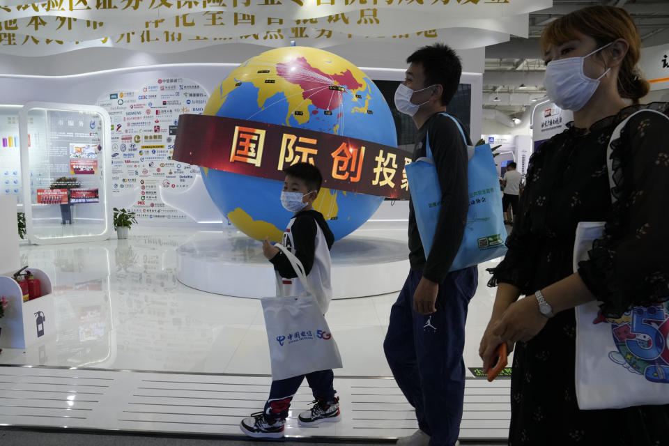Visitors walk by a globe depicting the reach of China's financial services around the world during the China International Fair for Trade in Services (CIFTIS) in Beijing, China, Monday, Sept. 6, 2021. The ruling Communist Party's campaign to tighten control over China's industries and reduce use of foreign technology is slashing economic growth, a foreign business group warned Thursday, Sept. 22 and it appealed to Beijing to reverse course and open state-dominated markets wider. (AP Photo/Ng Han Guan)