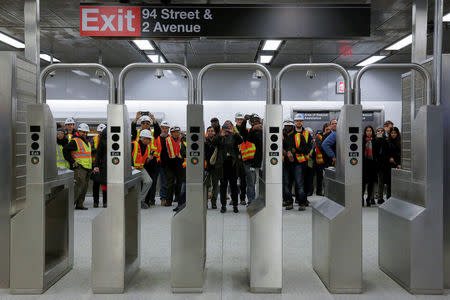 Workers take photos through the turnstyles at the 96th Street Station during a preview event for the Second Avenue subway line in Manhattan, New York City, U.S., December 22, 2016. REUTERS/Andrew Kelly