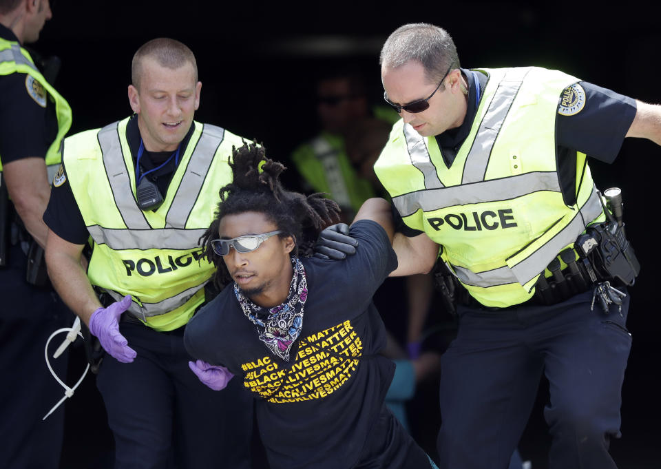 Police remove a demonstrator from outside the headquarters of CoreCivic, Monday, Aug. 6, 2018, in Nashville, Tenn. The Tennessee-based company is one of the nation's largest private prison operators and also runs eight immigration detention centers for Immigration and Customs Enforcement. (AP Photo/Mark Humphrey)