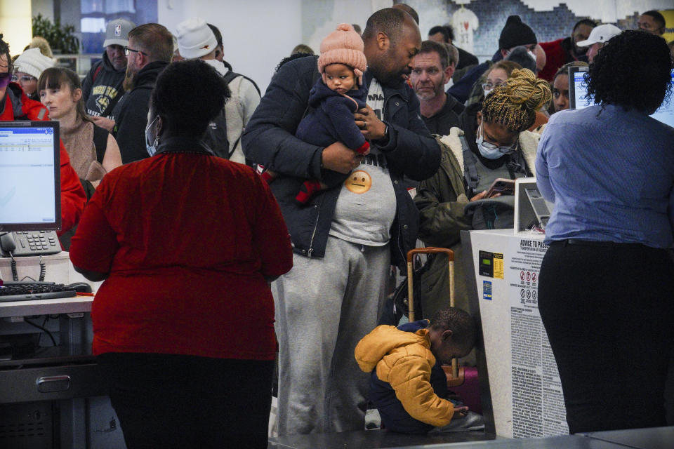 Southwest Airlines ticket holders Cameron Bradley, center, and his wife Kamilah Bradley, second from right, with their children Malaki, 3, and Kehlani, 8 months, try to rebook a flight to Atlanta after a cancellation at Laguardia Airport, Friday Dec. 23, 2022, in New York. "Literally we were in line trying to check our bags and the flight got cancelled," said Cameron, hoping to reach Atlanta for Kehlani's first meeting with her grandmother. "We can't fly anywhere- the nearest time would be after Christmas." (AP Photo/Bebeto Matthews)