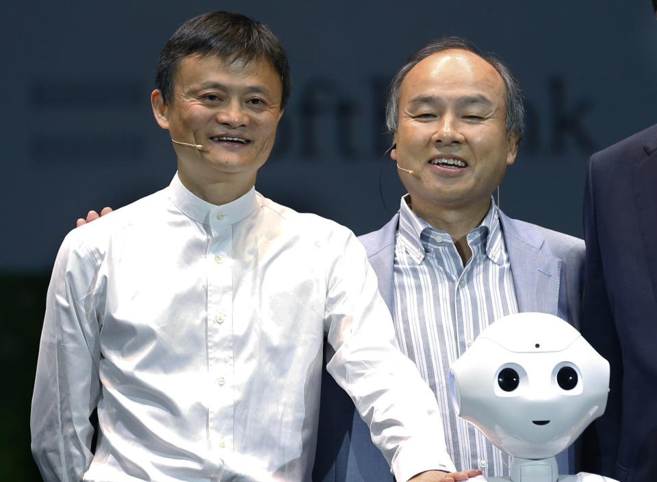 FILE - In this June 18, 2015, file photo, Softbank Corp. CEO Masayoshi Son, right, Alibaba Group Executive Chairman Jack Ma, left, of China with Foxconn Chairman and CEO Terry Gou of Taiwan pose for photographers with Softbank's Pepper robot during a press conference in Maihama, near Tokyo. Son, the chief executive of Japanese technology company SoftBank Group Corp. said Thursday, June 25, 2020, that he is stepping down from the board of Chinese e-commerce giant Alibaba. (AP Photo/Shizuo Kambayashi)