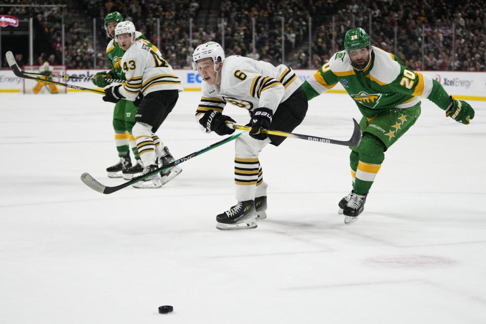 Boston Bruins defenseman Mason Lohrei (6) and Minnesota Wild left wing Pat Maroon (20) follow the puck during the first period of an NHL hockey game Saturday, Dec. 23, 2023, in St. Paul, Minn. (AP Photo/Abbie Parr)