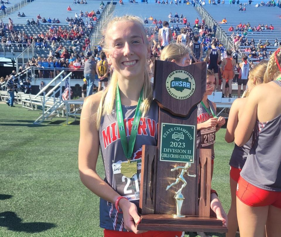 Minerva's Katie Ison holds the OHSAA Division II girls cross country state championship trophy after helping the Lions win their second title in three seasons last fall.