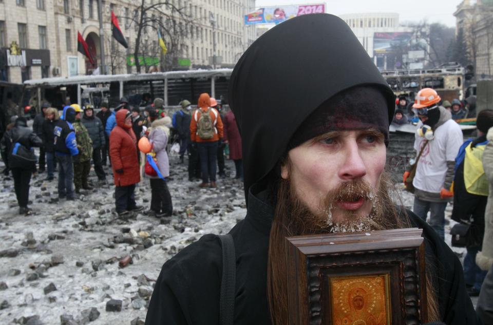 A clergyman stands near a barricade during a rally held by pro-European integration protesters in Kiev
