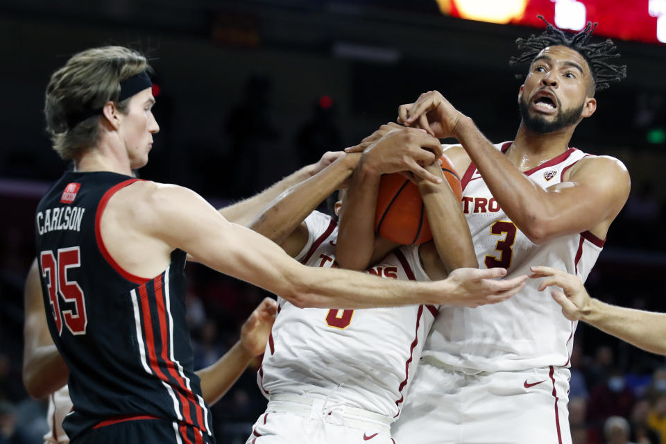 Southern California forward Isaiah Mobley, right, and center Lahat Thioune, center, vie for the ball against Utah center Branden Carlson, left, during the first half of an NCAA college basketball game in Los Angeles, Wednesday, Dec. 1, 2021. (AP Photo/Alex Gallardo)