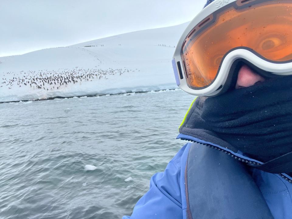 A selfie of the author on a zodiac with hundreds of penguins in the background.