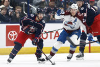 Columbus Blue Jackets forward Johnny Gaudreau (13) controls the puck in front of Colorado Avalanche forward Nathan MacKinnon during the first period of an NHL hockey game in Columbus, Ohio, Monday, April 1, 2024. (AP Photo/Paul Vernon)