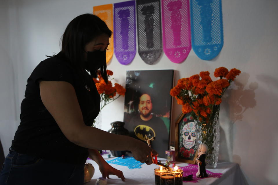 Pediatrician Kenya Navidad, 33, lights candles on a Day of the Dead altar for her husband Daniel Silva Montenegro, a doctor who died from symptoms related to COVID-19, at their home in Mexico City, Saturday, Oct. 31, 2020. The weekend holiday isn't the same in a year so marked by death in a country where more than 90,000 people have died of COVID-19, many cremated rather than buried and with cemeteries forced to close. (AP Photo/Ginnette Riquelme)