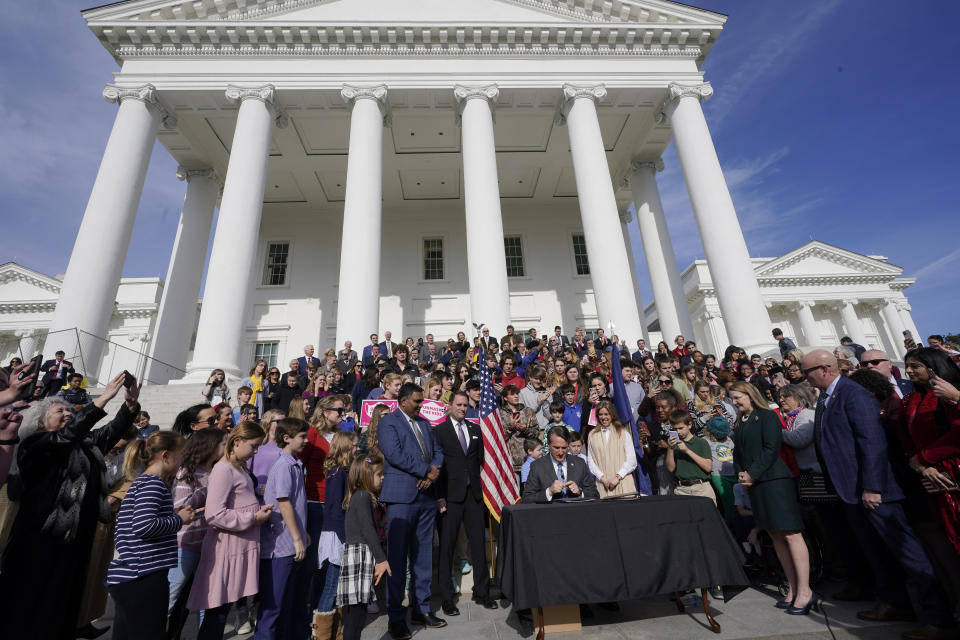 Virginia Gov. Glenn Youngkin, seated center, signs a bill that bans mask mandates in public schools in Virginia on the steps of the Capitol Wednesday Feb. 16, 2022, in Richmond, Va. (AP Photo/Steve Helber)