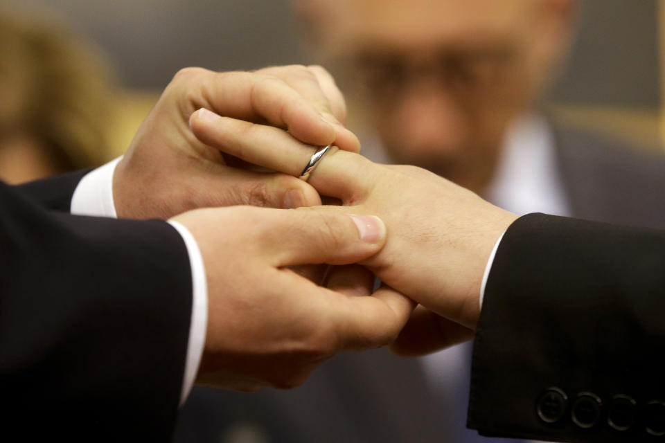 FILE - Mauro Cioffari, left, puts a wedding ring on his partner Davide Conti's finger as their civil union is being registered by a municipality officer during a ceremony in Rome's Campidoglio Capitol Hill on May 21, 2015 file photo. (AP Photo/Gregorio Borgia, file)