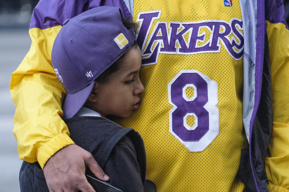 Eric Mascarenhas comforts his son Nicolas at a memorial for Kobe Bryant near Staples Center Monday, Jan. 27, 2020, in Los Angeles. Bryant, the 18-time NBA All-Star who won five championships and became one of the greatest basketball players of his generation during a 20-year career with the Los Angeles Lakers, died in a helicopter crash Sunday. (AP Photo/Ringo H.W. Chiu)