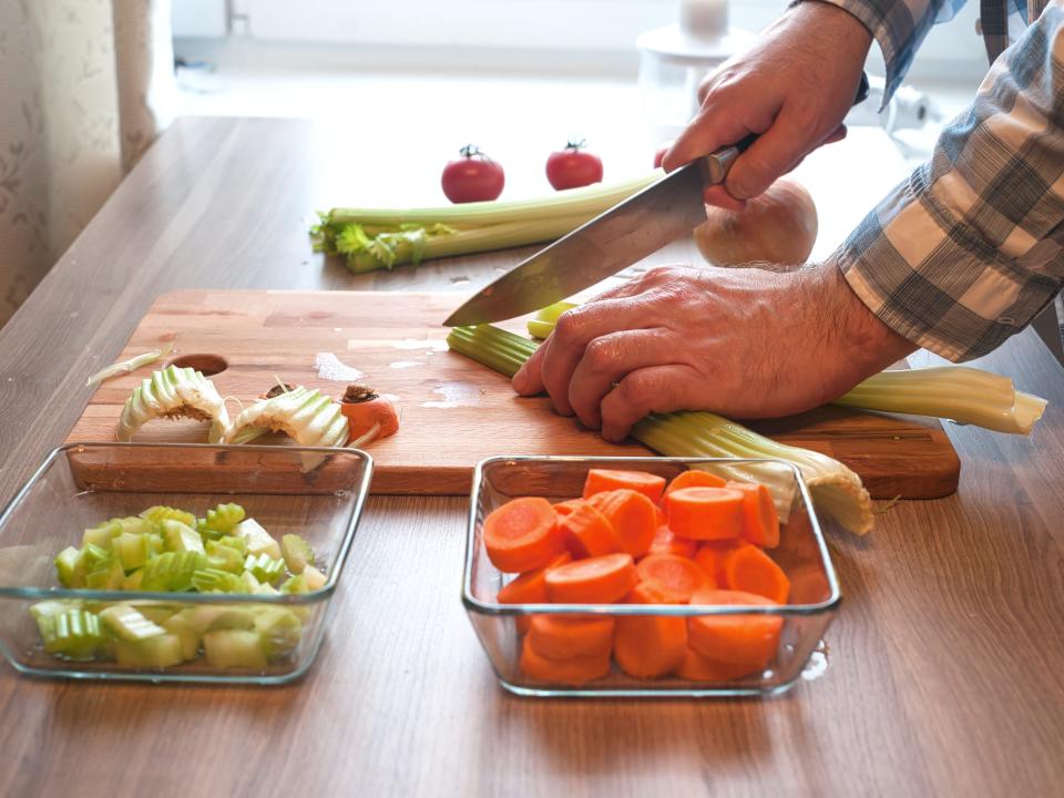 Person chopping celery and carrots.