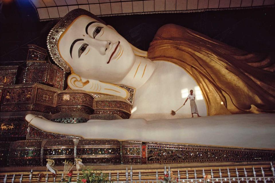 A worker cleaning a Buddha in a temple in Myanmar, circa 1971