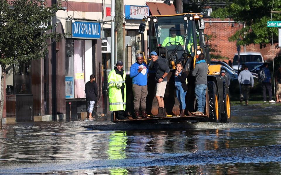 A frontend loader evacuates a family on Mamaroneck Avenue in Mamaroneck Sept. 2, 2021. Rains from Ida flooded the area overnight.