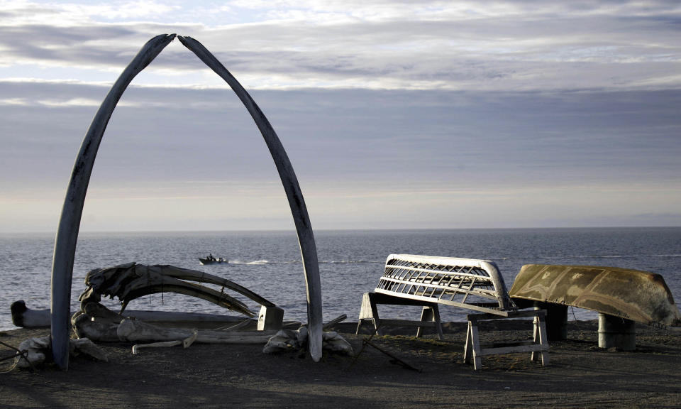 FILE - A boat moves past a skin boat display near whale bones and an arch made of a whale jaw on the beach in a town that was known as Barrow, Alaska, Aug. 12, 2005. After tidal surges and high winds from the remnants of a rare typhoon caused extensive flood damage to homes along Alaska's western coast in September, the U.S. government stepped in to help residents largely Alaska Natives repair property damage. Residents who opened Federal Emergency Management Agency brochures expecting to find instructions on how to file for aid in Alaska Native languages like Yup'ik or Inupiaq instead were reading nonsensical phrases. (AP Photo/Al Grillo, File)