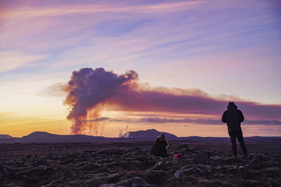 People watch from the north as the volcano erupts near Grindavík, Iceland, Sunday Jan. 14, 2024. A volcano has erupted in southwestern Iceland, sending semi-molten rock spewing toward a nearby settlement for the second time in less than a month. Iceland's Icelandic Meteorological Office says the eruption Sunday came after a swarm of earthquakes near the town of Grindavik. (AP Photo/ Marco Di Marco)