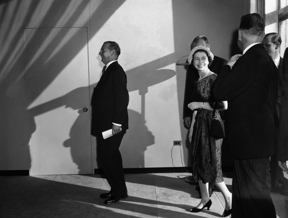 The sun casts a shadow across the face of Britain's Queen Elizabeth II, as she turns to bid farewell to officials and delegates at United Nations, New York, on Oct. 21, 1957. (AP Photo)