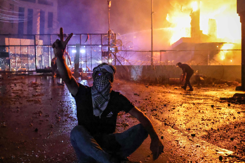A Lebanese protester sitting in front of a building on fire near the US embassy near Beirut (AFP via Getty Images)