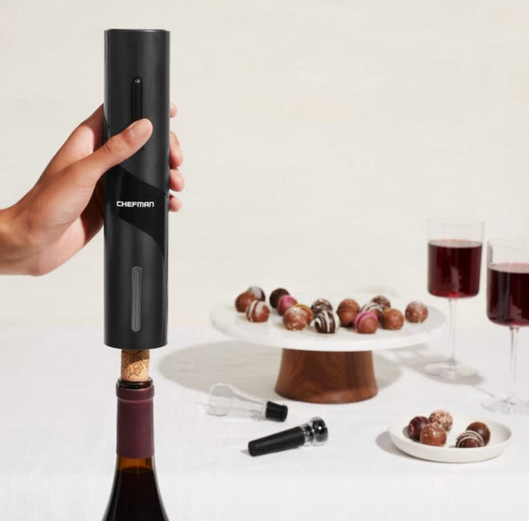 black electric wine opener next to chocolates and wine glasses