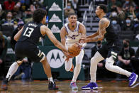 Milwaukee Bucks forward Jordan Nwora, left, fouls Sacramento Kings guard Tyrese Haliburton (0) as Bucks guard George Hill, right, closes in during the first half of an NBA basketball game Saturday, Jan. 22, 2022, in Milwaukee. (AP Photo/Jon Durr)