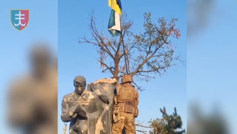 A member of the Ukrainian army installs Ukrainian flag in Urozhaine