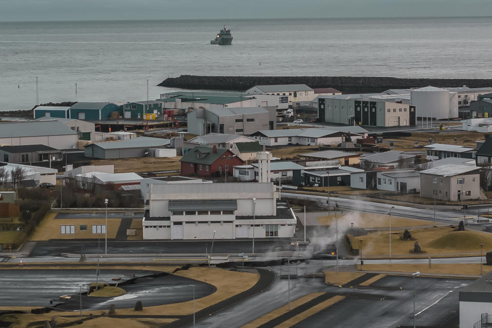 This image taken with a drone shows the town of Grindavik, Iceland, as a Coast Guard vessel patrol, Thursday, Nov. 16, 2023. Residents of a fishing town in southwestern Iceland have left their homes after increasing concern about a potential volcanic eruption caused civil defense authorities to declare a state of emergency in the region. Iceland's Meteorological Office says police decided to evacuate Grindavik after recent seismic activity in the area moved south toward the town. (AP Photo/Bjorn Steinbekk)