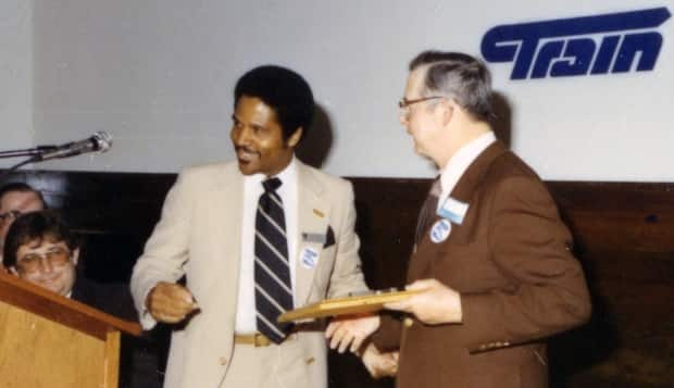 Oliver Bowen receives a gift as Ralph Klein, who served as premier and Calgary mayor, looks on.