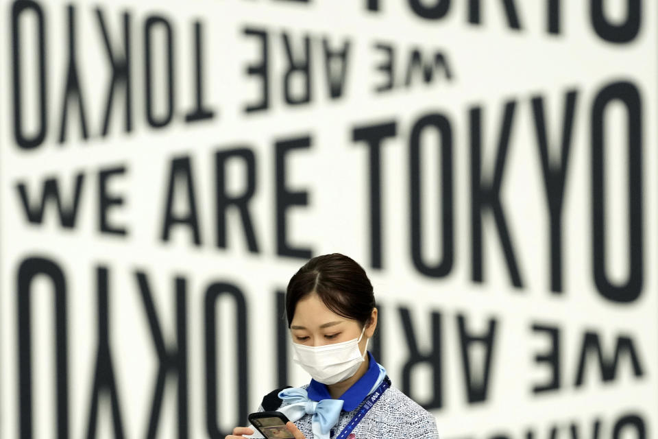 An employee wearing a protective mask to help curb the spread of the coronavirus walks through Haneda Airport Monday, Aug. 2, 2021, in Tokyo. (AP Photo/Eugene Hoshiko)