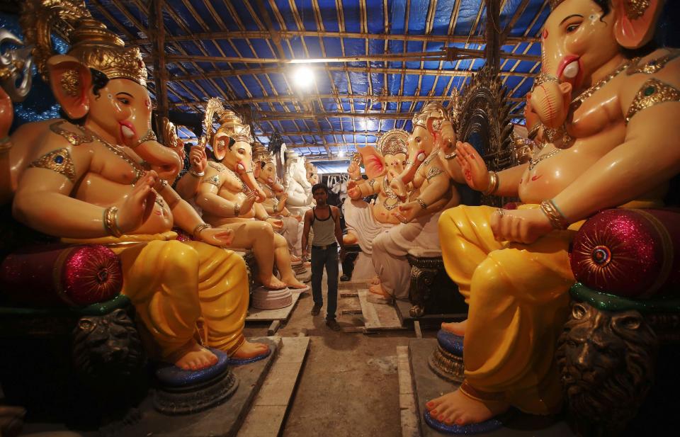 An artisan walks past the idols of Hindu elephant god Ganesh, the deity of prosperity, kept inside a workshop in Mumbai