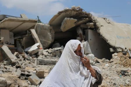 A Palestinian woman looks on as she stands in front of the ruins of her house, that witnesses said was destroyed by Israeli shelling during a 50-day war last summer, in Khan Younis in the southern Gaza Strip July 2, 2015. REUTERS/Ibraheem Abu Mustafa