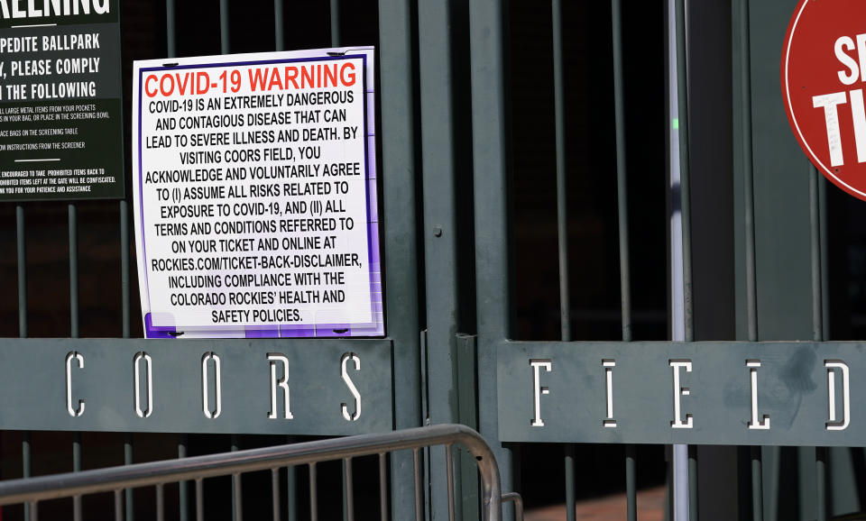 Signs hang on the first-base gates of Coors Field as one of the steps to stop the spread of the coronavirus as fans return for the first inning of a baseball game between the Los Angeles Dodgers and the Colorado Rockies Thursday, April 1, 2021, in Denver. (AP Photo/David Zalubowski)