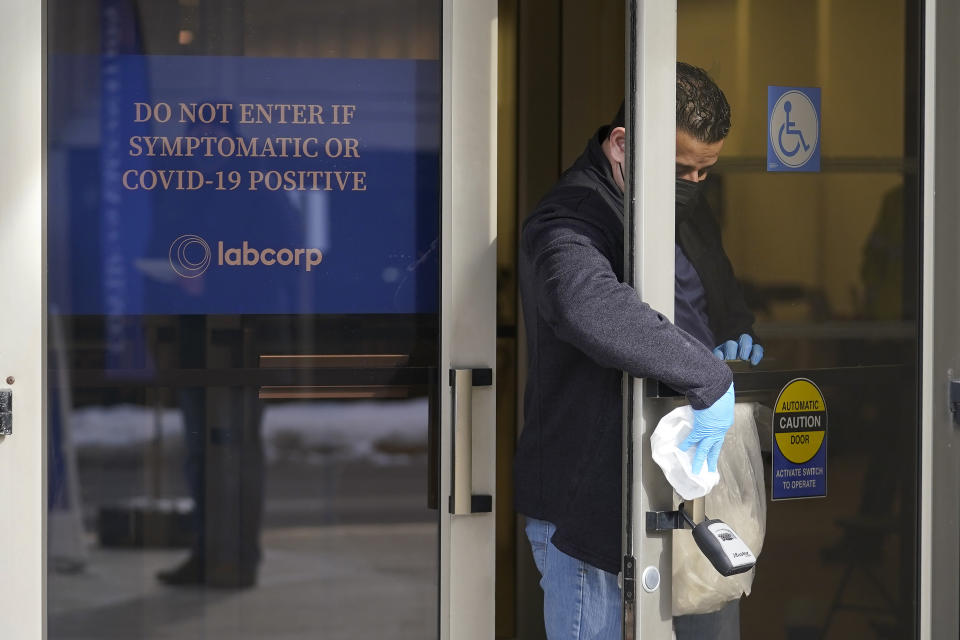 A worker sanitizes a door at an entrance to a COVID-19 vaccination site, Monday, Feb. 22, 2021, in Natick, Mass. (AP Photo/Steven Senne)