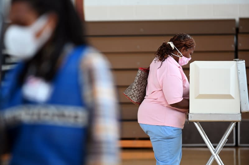 A voter wearing a mask casts a ballot on D.C.'s primary election day in Washington