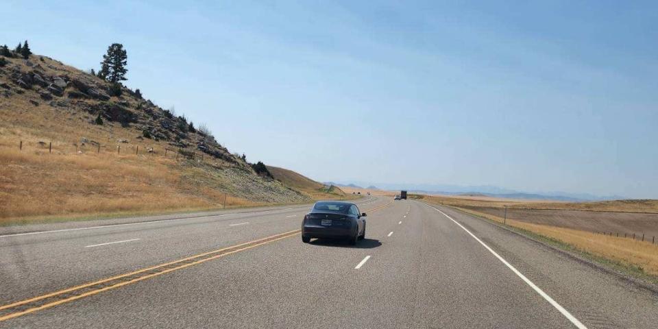 The Tesla is shown driving on a highway in Montana