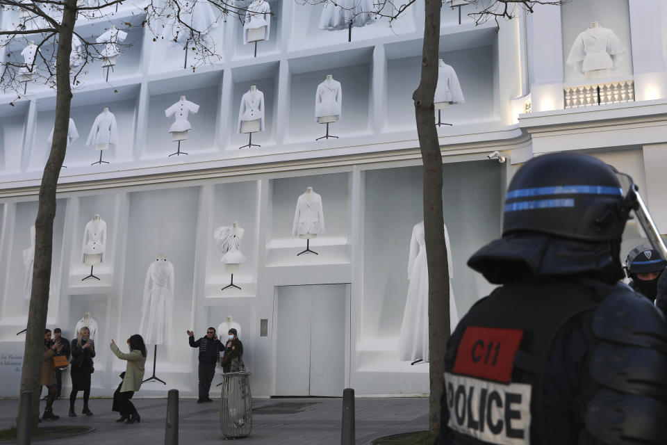 People take pictures during a protest on the Champs-Elysees avenue, Saturday, Feb.12, 2022 in Paris. Paris police intercepted at least 500 vehicles attempting to enter the French capital in defiance of a police order to take part in protests against virus restrictions inspired by the Canada's horn-honking "Freedom Convoy." . (AP Photo/Adrienne Surprenant)