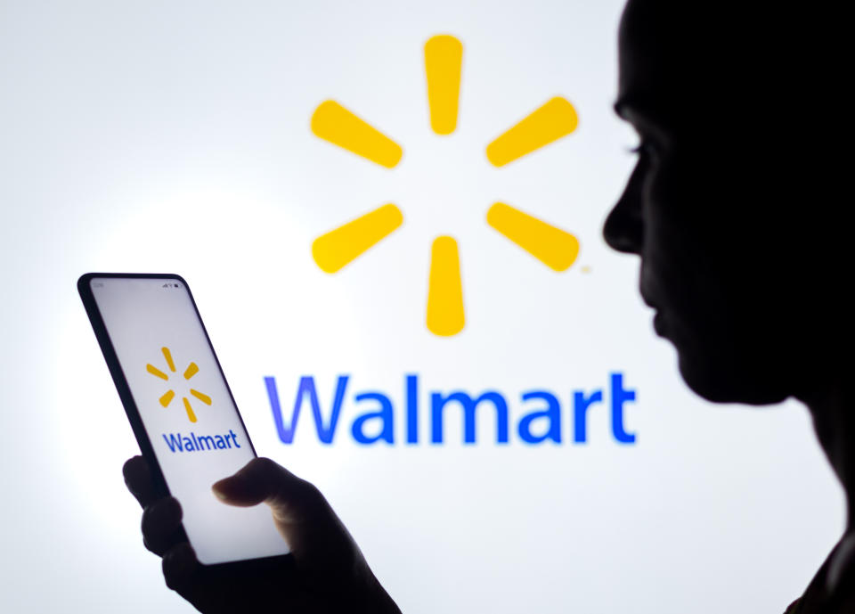 BRAZIL - 2022/03/30: In this photo illustration, a woman's silhouette holds a smartphone with the Walmart logo displayed on the screen and in the background. (Photo Illustration by Rafael Henrique/SOPA Images/LightRocket via Getty Images)